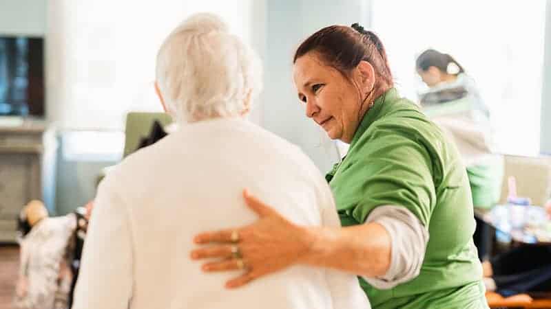 Staff member escorting senior woman